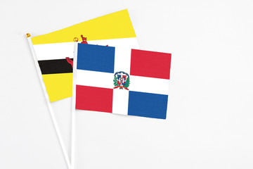 Dominican Republic and Brunei stick flags on white background. High quality fabric, miniature national flag. Peaceful global concept.White floor for copy space.