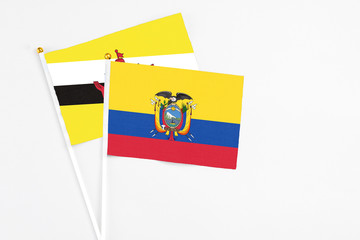 Ecuador and Brunei stick flags on white background. High quality fabric, miniature national flag. Peaceful global concept.White floor for copy space.