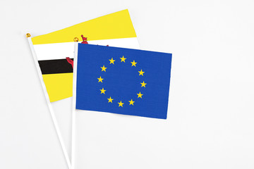 European Union and Brunei stick flags on white background. High quality fabric, miniature national flag. Peaceful global concept.White floor for copy space.