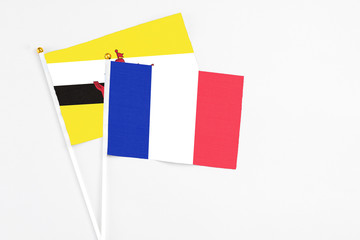 France and Brunei stick flags on white background. High quality fabric, miniature national flag. Peaceful global concept.White floor for copy space.