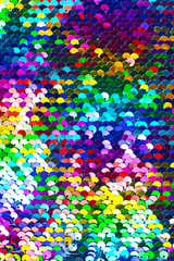 Texture of rainbow shiny sequins. Fashionable bright fabric with sequins. Selective focus.