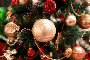 New Years colorful decoration ornaments on Christmas tree. Room decorated to christmas celebration, holiday scene with various shapes, multicolored balls, decorative sparkle bows and bird on tree.