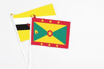 Grenada and Brunei stick flags on white background. High quality fabric, miniature national flag. Peaceful global concept.White floor for copy space.