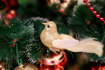 New Years colorful decoration ornaments on Christmas tree. Room decorated to christmas celebration, holiday scene with various shapes, multicolored balls, decorative sparkle bows and bird on tree.