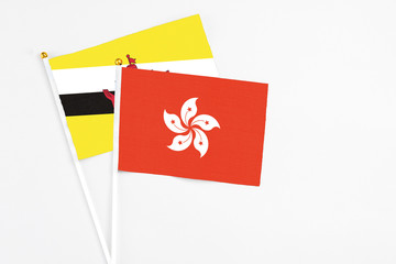 Hong Kong and Brunei stick flags on white background. High quality fabric, miniature national flag. Peaceful global concept.White floor for copy space.