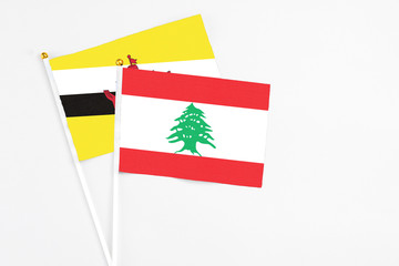 Lebanon and Brunei stick flags on white background. High quality fabric, miniature national flag. Peaceful global concept.White floor for copy space.