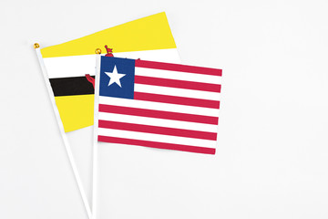 Liberia and Brunei stick flags on white background. High quality fabric, miniature national flag. Peaceful global concept.White floor for copy space.