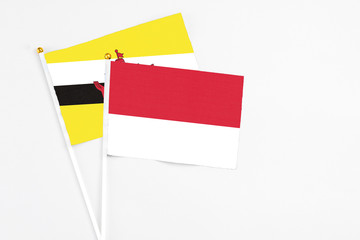 Monaco and Brunei stick flags on white background. High quality fabric, miniature national flag. Peaceful global concept.White floor for copy space.