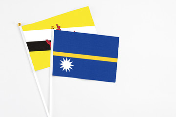 Nauru and Brunei stick flags on white background. High quality fabric, miniature national flag. Peaceful global concept.White floor for copy space.