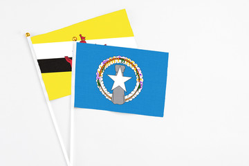 Northern Mariana Islands and Brunei stick flags on white background. High quality fabric, miniature national flag. Peaceful global concept.White floor for copy space.