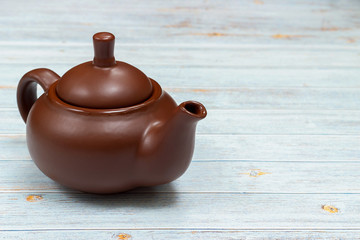 Brown clay teapot on a blue wooden background.