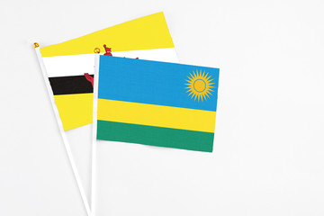 Rwanda and Brunei stick flags on white background. High quality fabric, miniature national flag. Peaceful global concept.White floor for copy space.
