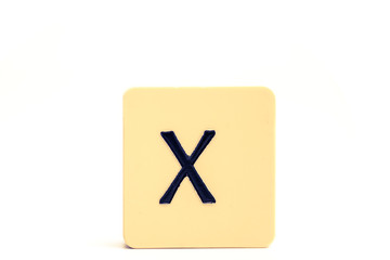Dark letter X on a pale yellow square block isolated on white background