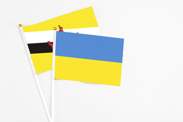 Ukraine and Brunei stick flags on white background. High quality fabric, miniature national flag. Peaceful global concept.White floor for copy space.