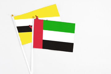 United Arab Emirates and Brunei stick flags on white background. High quality fabric, miniature national flag. Peaceful global concept.White floor for copy space.