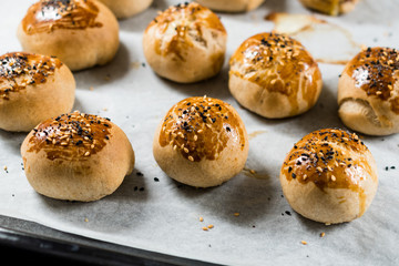 Homemade Turkish Pastries Pogaca with Black Cumin and Sesame Seeds on Baking Paper Sheet with Tray.