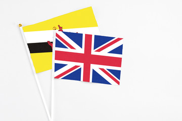 United Kingdom and Brunei stick flags on white background. High quality fabric, miniature national flag. Peaceful global concept.White floor for copy space.