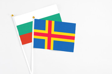 Aland Islands and Bulgaria stick flags on white background. High quality fabric, miniature national flag. Peaceful global concept.White floor for copy space.