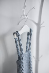 Knitted clothing made of sheep wool for young children who were just born. Hanging on a hanger on a deckboard tree on a white background.