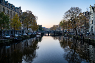 Amsterdam, Netherlands - Buildings and house boats along canal during an early autumn fall morning in the Jordaan neighborhood