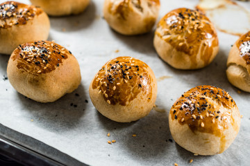 Homemade Turkish Pastries Pogaca with Black Cumin and Sesame Seeds on Baking Paper Sheet with Tray.