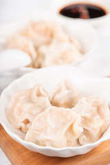 Obraz na płótnie Canvas Fresh, delicious boiled pork, shrimp gyoza dumplings on white background with soy sauce and chopsticks, close up, lifestyle. Homemade design concept.