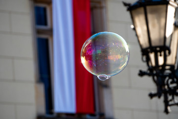Close up of the colorful soap bubble in the bright autumn day with polish national flag during independence in Wroclaw,