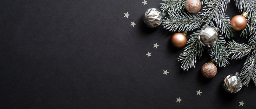 Christmas banner. Christmas tree branch decorated cooper and silver color balls on black background with confetti. Wide Xmas banner mockup, header, flyer