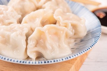 Fresh, delicious boiled pork, shrimp gyoza dumplings on white background with soy sauce and chopsticks, close up, lifestyle. Homemade design concept.