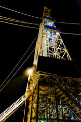 Oil and gas drilling rig with night lighting. Winter polar night. Blurred contours of snow-covered...
