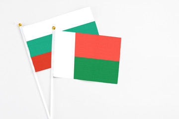 Madagascar and Bulgaria stick flags on white background. High quality fabric, miniature national flag. Peaceful global concept.White floor for copy space.