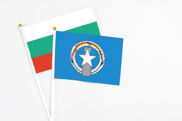 Northern Mariana Islands and Bulgaria stick flags on white background. High quality fabric, miniature national flag. Peaceful global concept.White floor for copy space.