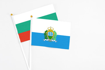 San Marino and Bulgaria stick flags on white background. High quality fabric, miniature national flag. Peaceful global concept.White floor for copy space.
