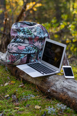 laptop and tourist backpack in forest