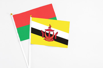 Brunei and Burkina Faso stick flags on white background. High quality fabric, miniature national flag. Peaceful global concept.White floor for copy space.