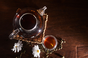 A teapot and a bowl of black tea on a dark board background