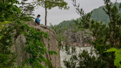 Teen girl standing on rock looking at mobile phone