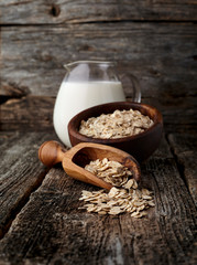 Oatmeal or oat flakes with milk on dark wooden table