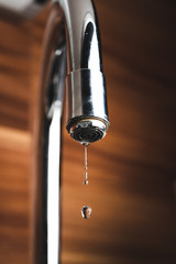 Metal tap and water drop close up. Lime stone in water.
