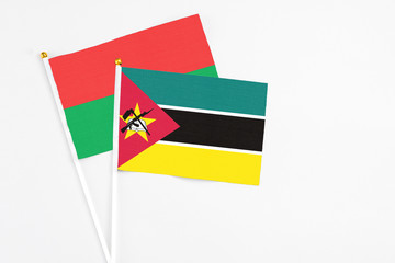 Mozambique and Burkina Faso stick flags on white background. High quality fabric, miniature national flag. Peaceful global concept.White floor for copy space.