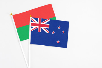 Fototapeta premium New Zealand and Burkina Faso stick flags on white background. High quality fabric, miniature national flag. Peaceful global concept.White floor for copy space.