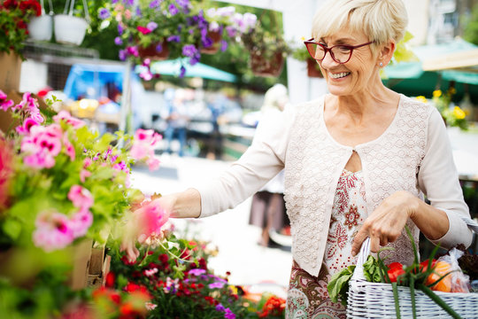 Attractive Senior Woman Shopping In An Outdoors Fresh Flowers Market