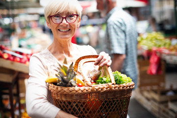 Picture of mature woman at marketplace buying vegetables