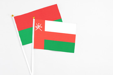 Oman and Burkina Faso stick flags on white background. High quality fabric, miniature national flag. Peaceful global concept.White floor for copy space.