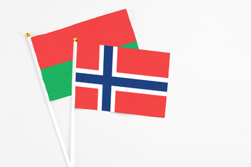 Obraz premium Norway and Burkina Faso stick flags on white background. High quality fabric, miniature national flag. Peaceful global concept.White floor for copy space.