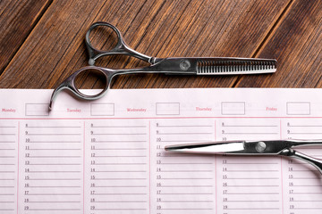 Business calendar for writing customers. Barber scissors on a clean diary. Barber tool and clean...