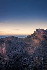 Tramuntana mountains at sunset. Single small house on top. Colourful landscape with golden light and beautiful sky. Mallorca, Spain.
