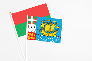 Saint Pierre And Miquelon and Burkina Faso stick flags on white background. High quality fabric, miniature national flag. Peaceful global concept.White floor for copy space.