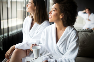 Women relaxing and drinking tea in robes during wellness weekend