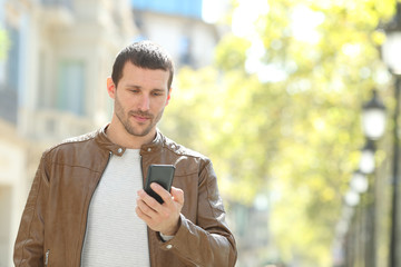 Serious adult man checking smart phone in the street